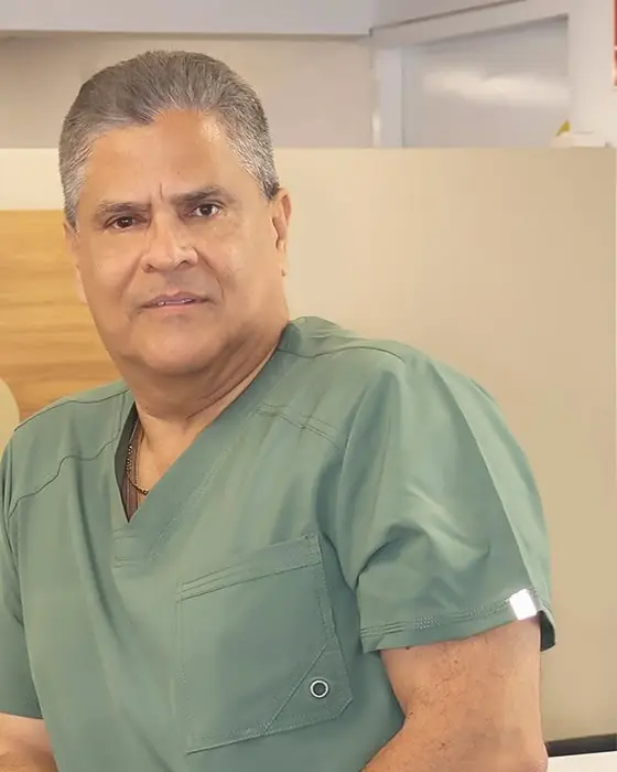 El Dr. Alberto Saravia Zárate, vestido con uniforme quirúrgico verde, en su consultorio.