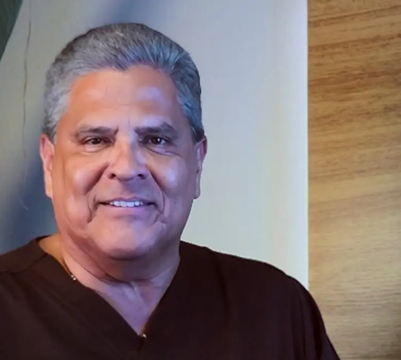 El Dr. Alberto Saravia Zárate, médico dermatólogo, con uniforme oscuro y expresión amable.